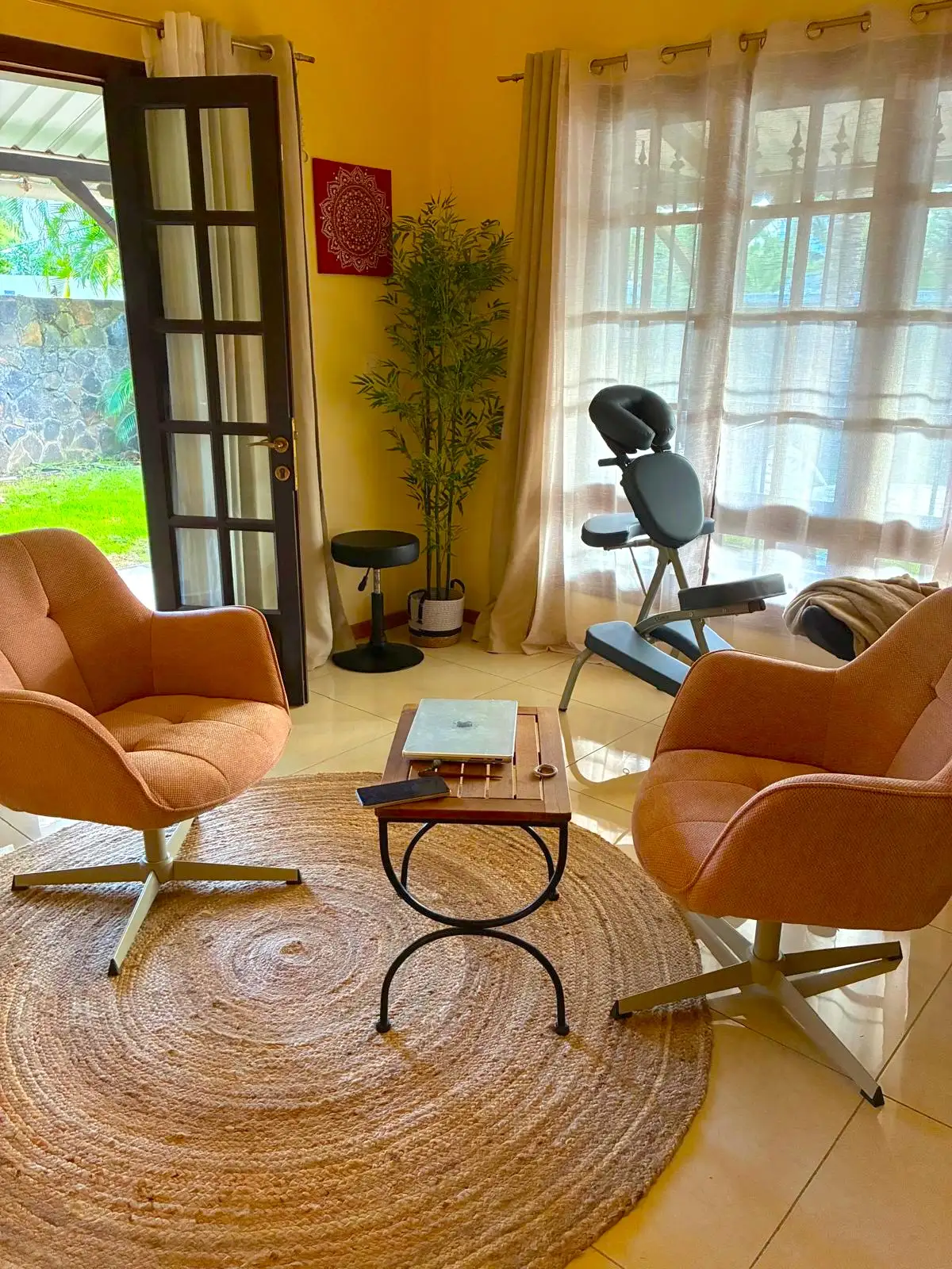 L’espace bien-être de Nathalie à Bain Bœuf, baigné de lumière : deux fauteuils, une table basse, un tapis rond